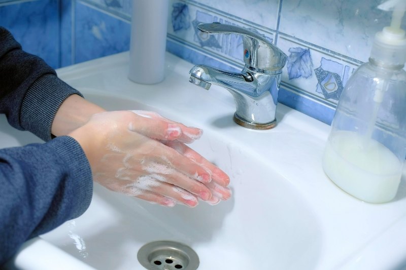 Child boy washing hands with antibacterial soap in sink